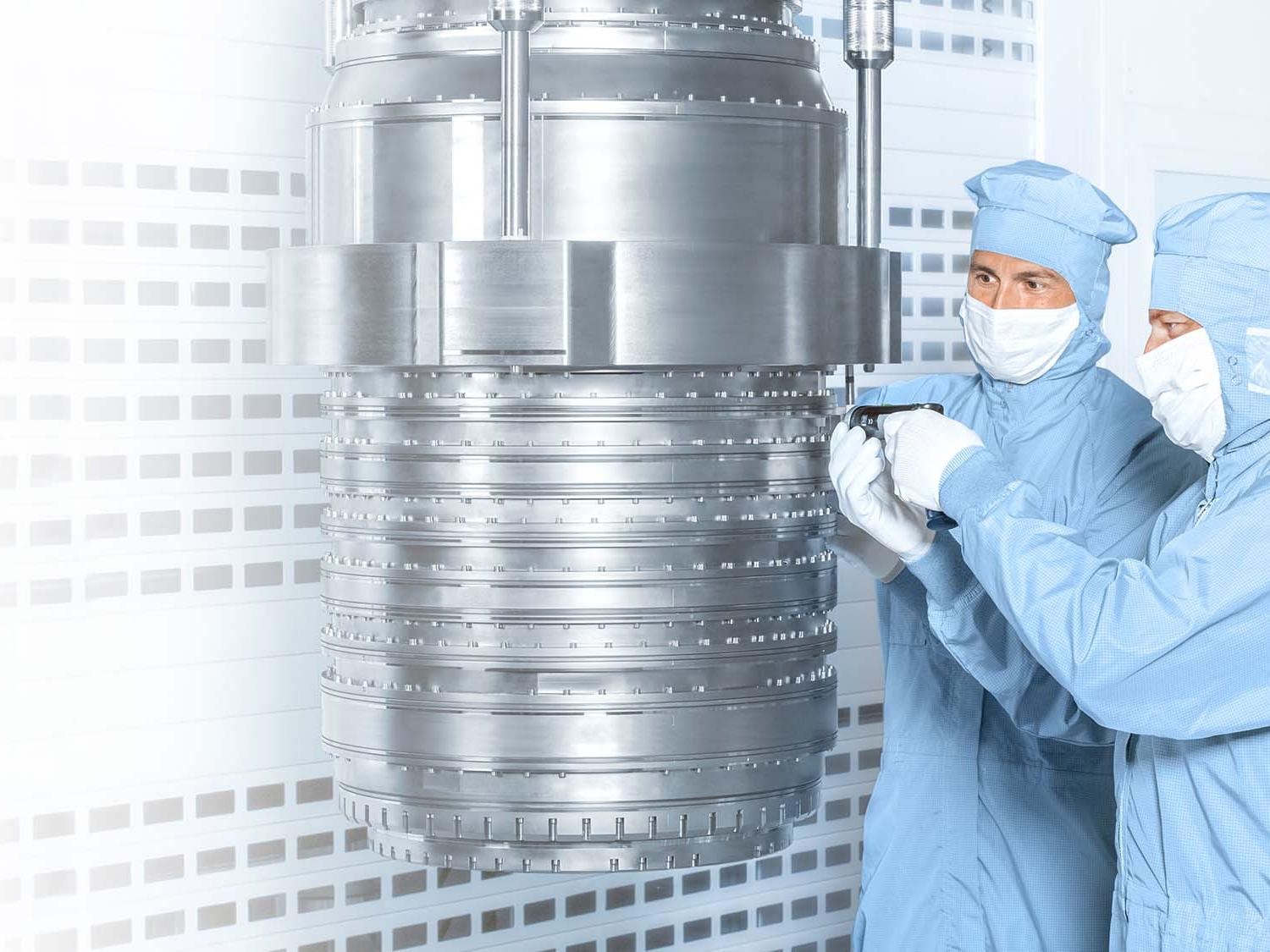 Two employees work on a DUV lithography in the clean room at ZEISS SMT.