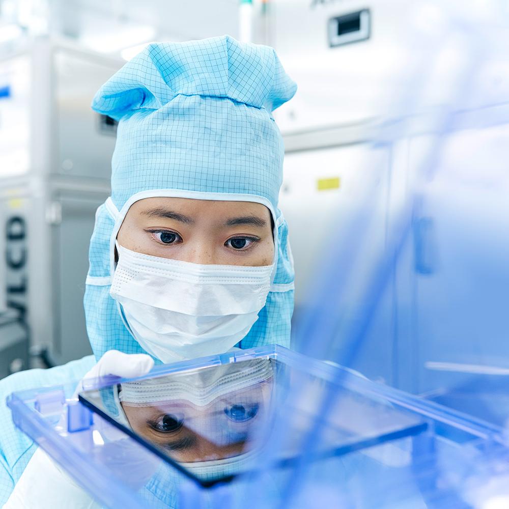 一名員工拿著光罩在無塵室內工作