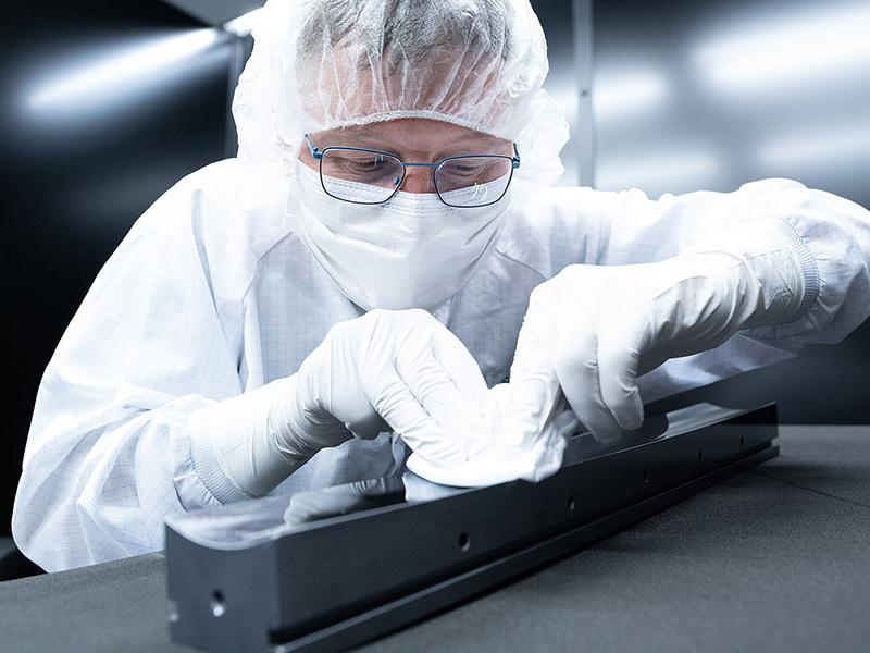 An employee works on the synchrotron optics and cleans the product in the darkroom. 