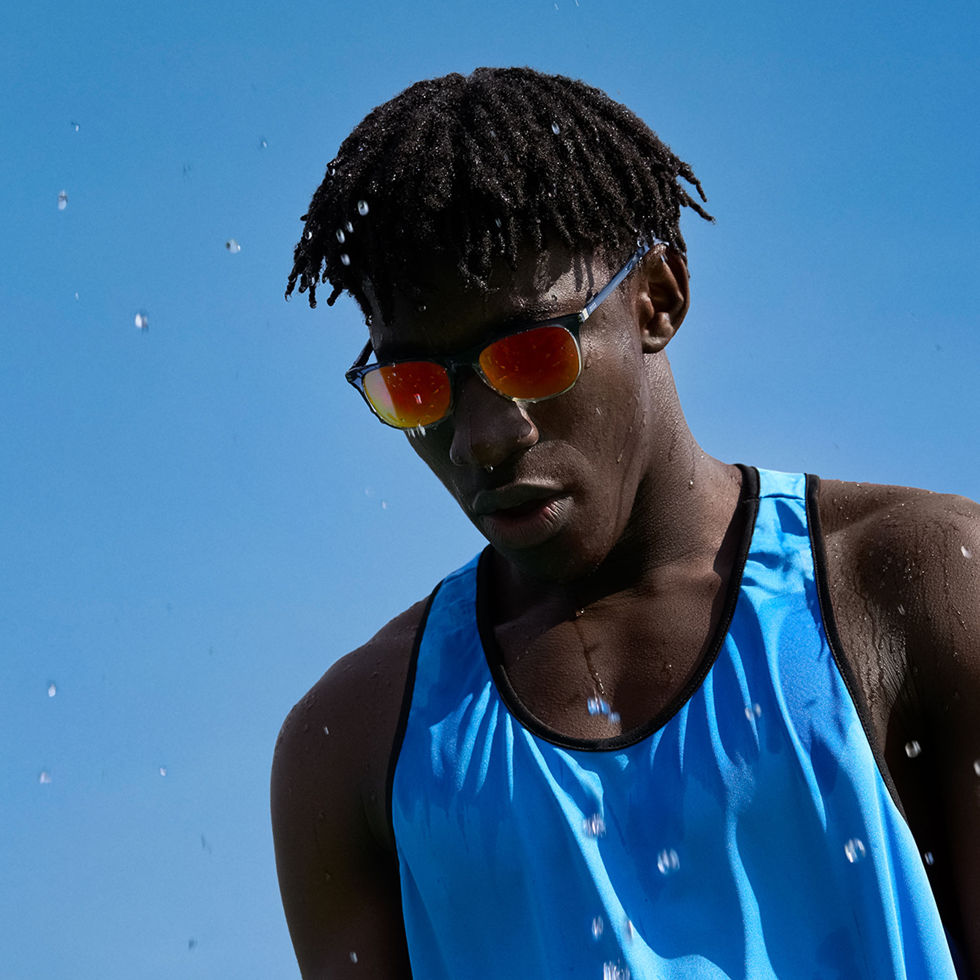 一位年輕男性穿著運動服，並戴著棕橙色調的 ZEISS Performance 太陽眼鏡，站在藍天底下。