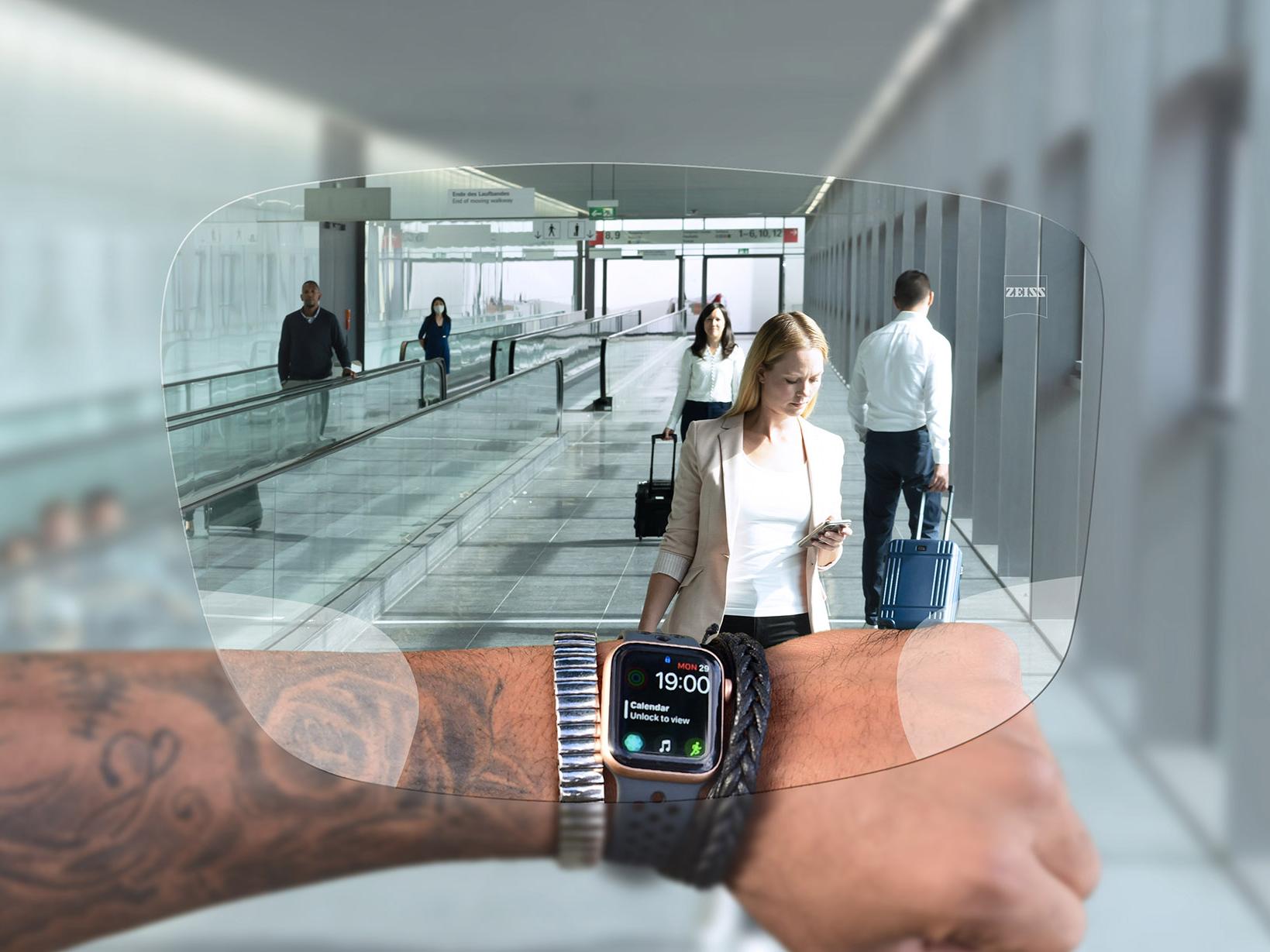 透過蔡司SmartLife智銳數位鏡片看手錶的人 背景可看見人們推著行李箱上下電扶梯的典型機場情景。 