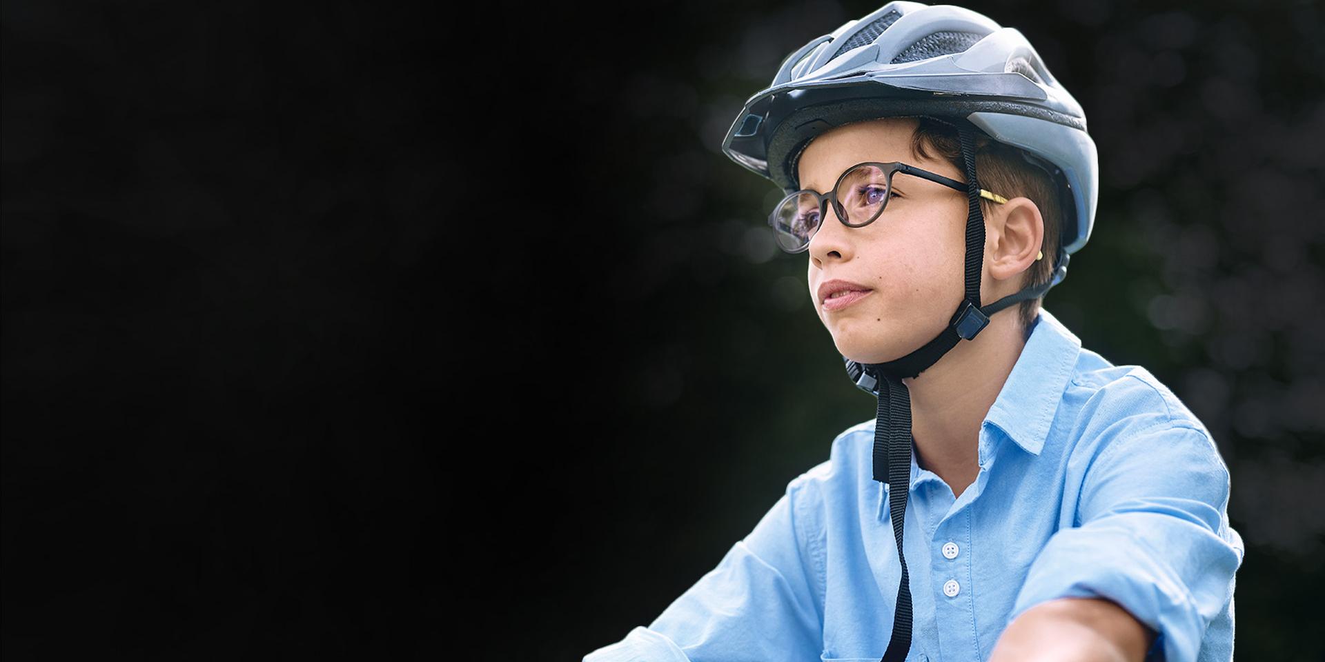 戴著眼鏡和安全帽的小男孩正在騎自行車。