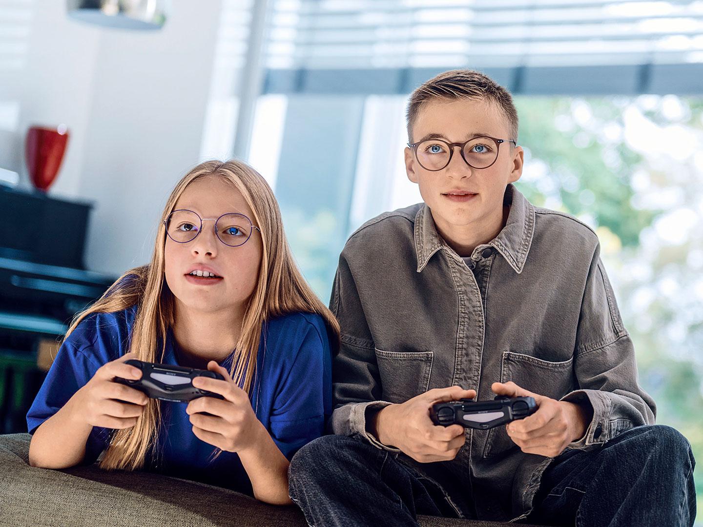 一名少女和一名少年正在玩遊戲機的電子遊戲。