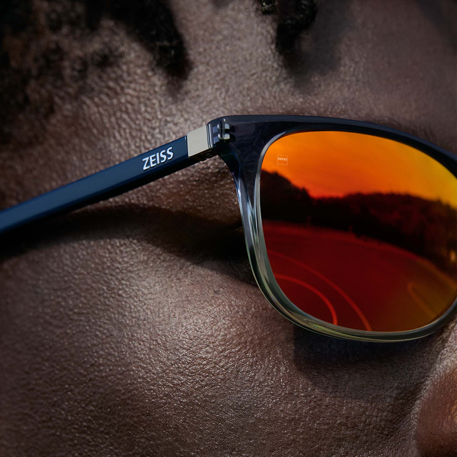 特寫：一位男性戴著具有橙色 ZEISS DuraVision Mirror UV 太陽眼鏡塗層的 ZEISS 眼鏡。