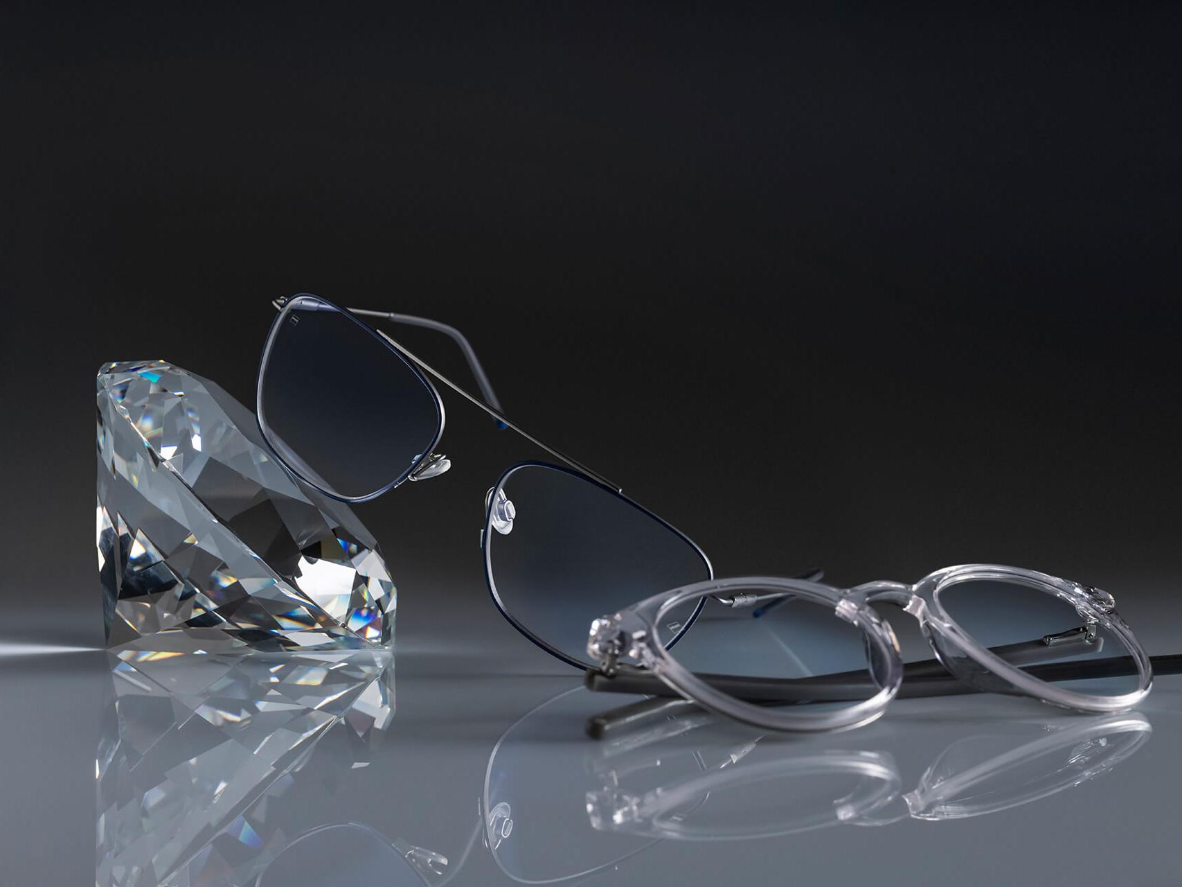 兩副蔡司眼鏡，配備有史以來最堅硬的蔡司鍍膜：DuraVision® Platinum。一副眼鏡放在水晶上，另一副平放在地面。兩者均配有無藍色反光的清澈鏡片。