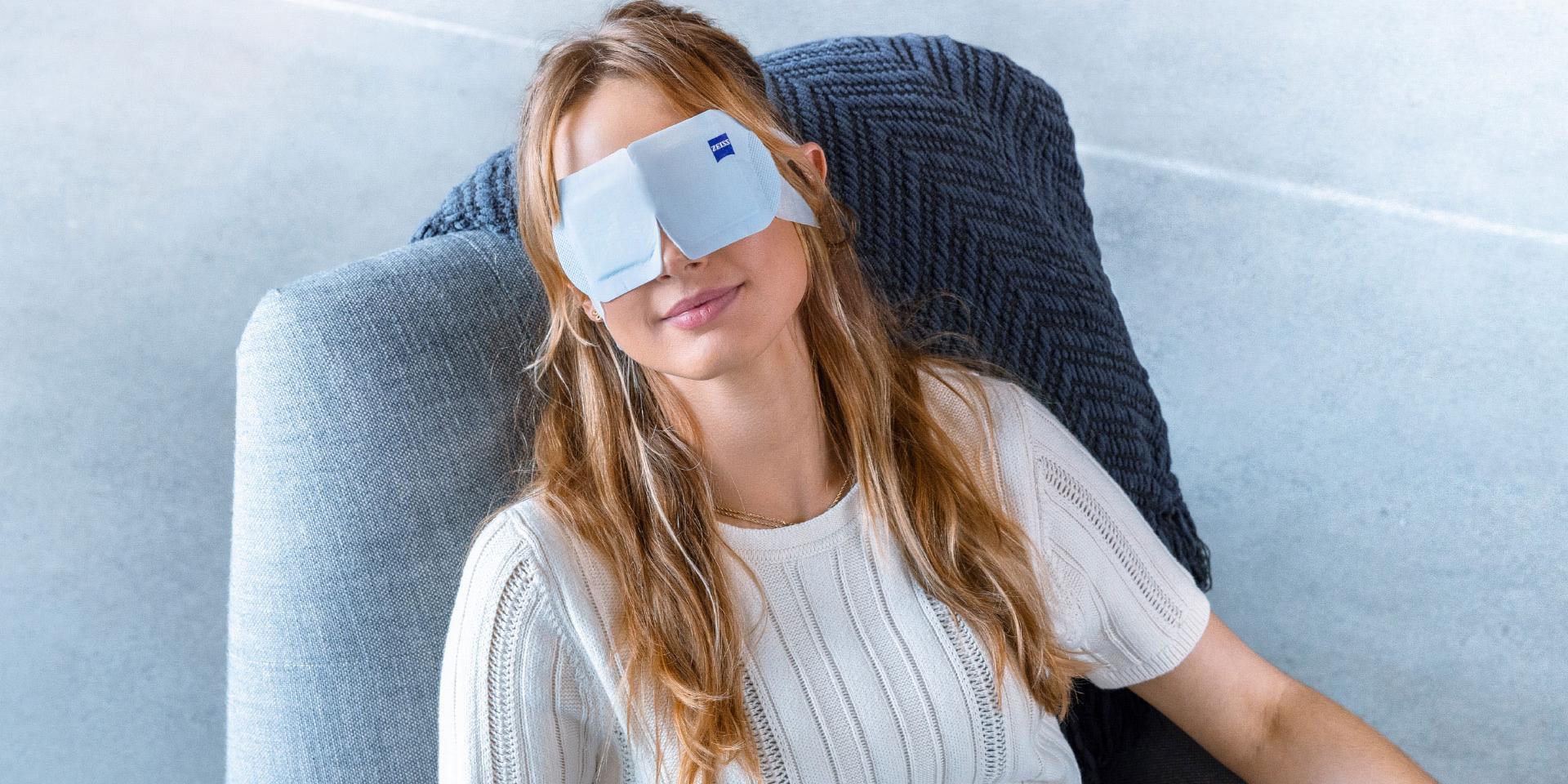 一位女士戴著 ZEISS 蒸氣眼罩，在椅子上放輕鬆。